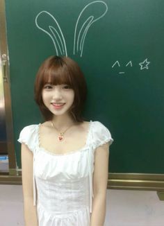 a young woman standing in front of a blackboard