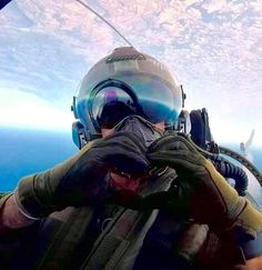 a man in a fighter jet flying through the air with his hands on his face