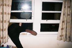 a person leaning against a window with their feet on the windowsill