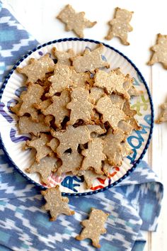 a plate full of star shaped cookies sitting on a blue and white table cloth next to some cut up ones