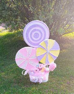 three umbrellas are sitting in the grass near a basket full of toys and gifts