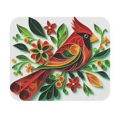 a red bird with green leaves and flowers on it's back is sitting on a white surface