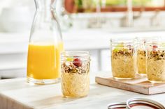 four jars filled with oatmeal sitting on top of a counter next to a glass pitcher