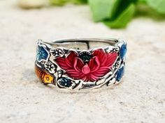 This sterling silver ring is adorned with an engraved lotus flower and beautiful Enamel Color !  If you're looking for authentic jewelry of the utmost quality, then this ring is for you. It consists of the finest 925 solid sterling silver, also nickel free .  For men and women. Size 7 to size 9½. Adjustable.  Ring weight : 4.4 grams  Ring Width : 9mm For other Sterling Silver rings , click here : https://www.etsy.com/shop/tibicollection?section_id=24624386 Return to the home page, click here : h Silver Flower Enamel Ring As A Gift, Traditional Handmade Flower Ring As Gift, Lotus Ring, Indian Bridal Jewelry Sets, Wide Band Ring, Sterling Silver Rings Bands, Thumb Ring, Authentic Jewelry, Statement Ring Silver