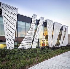 the exterior of a modern building with white perfored panels