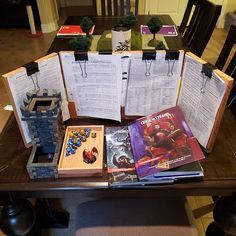 a table topped with lots of books on top of a wooden table covered in binders