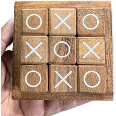 a hand holding a wooden tic - tac toe game