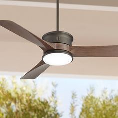 a ceiling fan with two lights on top of it in front of some trees and bushes