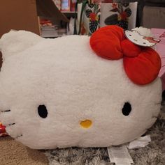 a large white hello kitty stuffed animal with a red bow on it's head