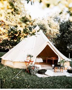 a white tent sitting on top of a lush green field next to a wooden table