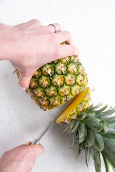 a person cutting up a pineapple with a pair of scissors on top of it