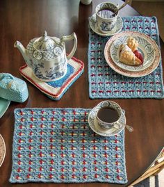 crocheted placemats and cups on a wooden table with teapot, coffee cup, and saucer