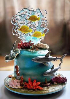 there is a blue cake decorated with fish and corals on the top, surrounded by other sea creatures