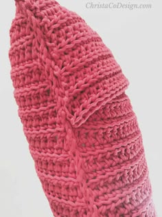 a pink crocheted sweater hanging from a hook