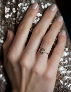 a woman's hand with a gold ring on top of her finger and silver sequins