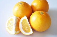 three oranges cut in half on a white surface