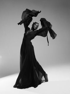 a woman in a long black dress is dancing