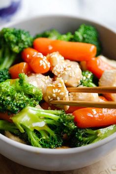 a bowl filled with broccoli, carrots and sesame seed chicken stir fry