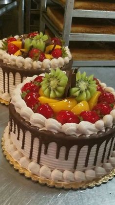 two cakes sitting on top of a table covered in chocolate frosting and fresh fruit