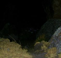 there is a light show in the dark sky above some rocks and dry grass on this path