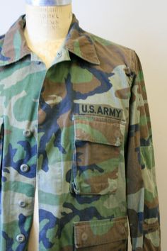 "Description: Vintage US Army camouflage jacket. Cotton. Long sleeves with a button front. It has four front pockets. Condition: In good condition, with no holes or stains. There is a chest patch missing (you can see where it was stitched on). Designer: n/a Stated Size: n/a Measurements: Armpit to armpit: 24\" Shoulder to shoulder: 19\" Sleeve length: 23\" Overall length: 29.5\" Waist: up to 54\" ---> If you need an order shipped by a particular date or shipped via a quicker method, please as Military Camouflage Outerwear With Buttons, Army Camouflage, Camouflage Jacket, Us Army, Military Jacket, Camouflage, Mens Jackets, Overalls, Vintage Outfits