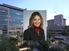 a woman is standing in front of a building with palm trees and buildings behind her