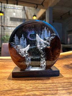 a snow globe with two birds and trees on the inside, sitting on a wooden table