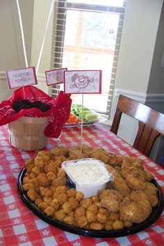 a table topped with a plate of food covered in tater tots and dip