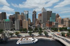 a large white boat floating on top of a river next to a tall city skyline