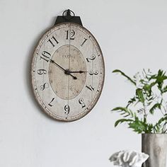 a clock hanging on the wall next to a potted plant