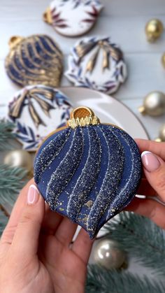 a hand holding a blue and gold ornament