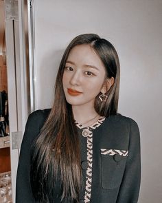 a woman with long hair standing in front of a mirror and looking at the camera