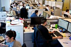 people working in an office cubicle with computers on the desks and other equipment