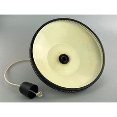 a black and white lamp on a gray surface with a cord attached to it's side