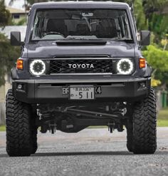 the front end of a gray toyota truck with its lights on and four wheel drive