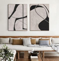 two paintings hang on the wall above a white couch and coffee table in a living room