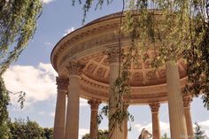 a woman standing in front of a gazebo with columns and trees around her head