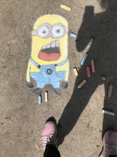 someone standing next to a chalk drawing of a minion