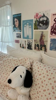 a stuffed dog sitting on top of a bed in a room with pictures on the wall