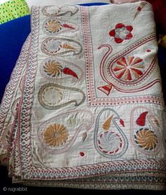 an old quilt is laying on top of a blue tablecloth with red, yellow and white designs