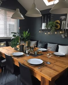 a dining room table is set with place settings for six people and the lights are hanging from the ceiling