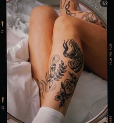 a woman with tattoos on her legs laying in bed next to a round glass mirror