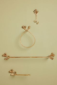 two gold - plated metal objects are displayed on a beige background, including an arrow