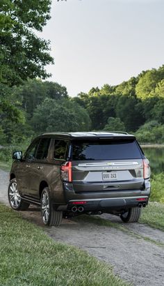 an suv parked on the side of a dirt road next to a body of water