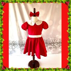 a red and white dress on a mannequin with holly wreaths around it