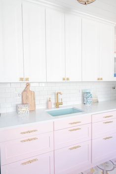 a kitchen with white cabinets and pink counter tops, gold handles on the faucet