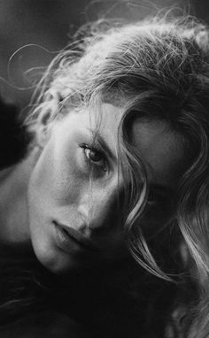 a black and white photo of a woman with her hair blowing in the wind,