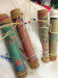 four different colored tubes wrapped in twine and tied with string on top of a white surface