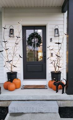 two pumpkins are sitting on the front steps next to a black door and some lights