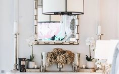 a white mantle with candles and flowers on it in front of a large mirror over the mantel